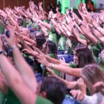 Participantes do evento com as mãos levantadas